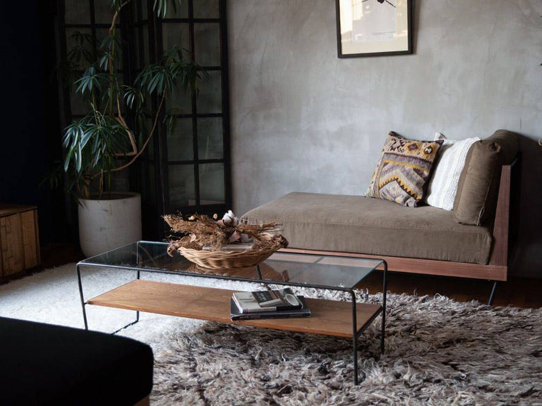 木製フロアに配置されたブラウンのウェルメカウチソファとクッションが調和するリビングルームのインテリア