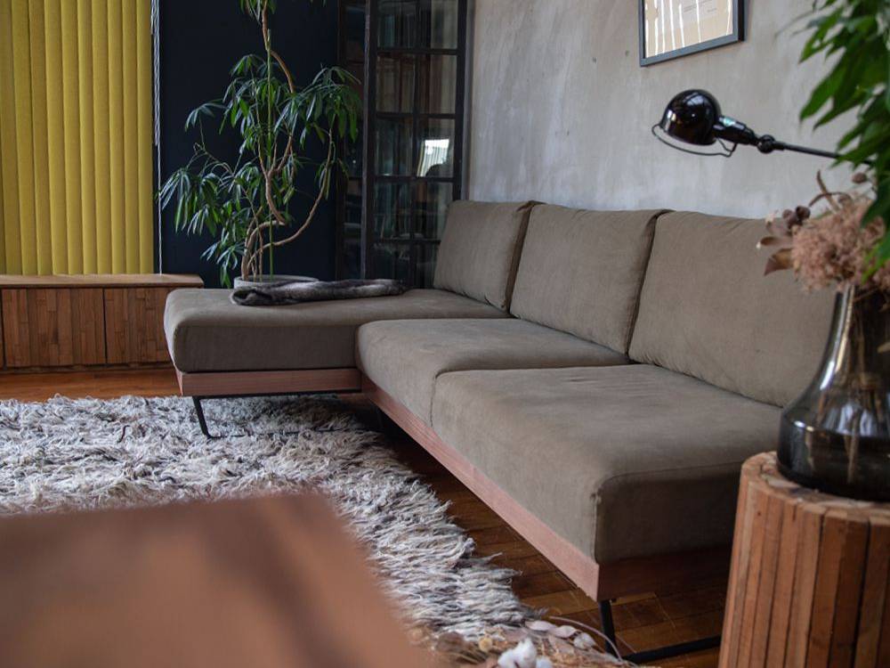 アデペシュのウェルメ カウチソファがナチュラルな木材と観葉植物と共にリビングルームに配置された画像