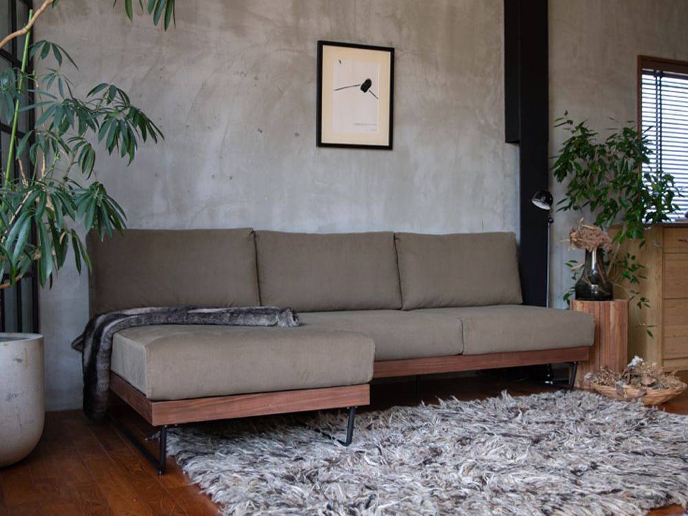 ウォルナットフローリングの上に配置されたアデペシュのウェルメ カウチソファがある快適なリビングルーム