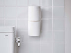 白色のスチール製トイレットペーパーホルダーが壁に取り付けられ、トイレットペーパーがセットされている様子
