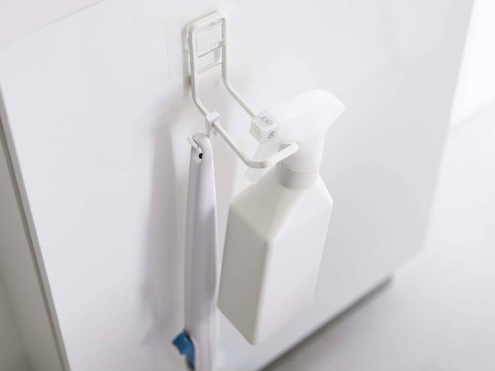 タワーのフィルムフックが浴室の陶器壁に取り付けられ、ソープディスペンサーやプラスチックボトルが掛かっている様子