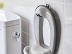 タワー型フィルムフックトイレ用品収納フックがバスルームの白色陶器トイレに取り付けられている様子