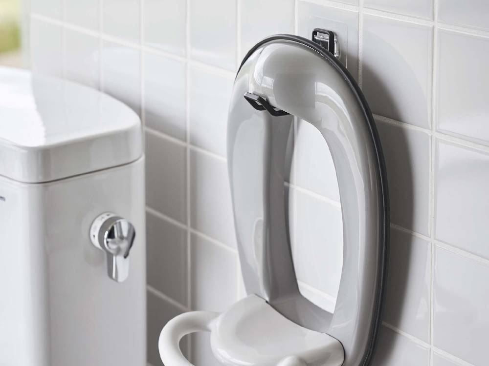 タワー型フィルムフックトイレ用品収納フックがバスルームの白色陶器トイレに取り付けられている様子