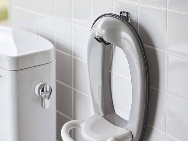 タワー型フィルムフックトイレ用品収納フックがバスルームの白色陶器トイレに取り付けられている様子