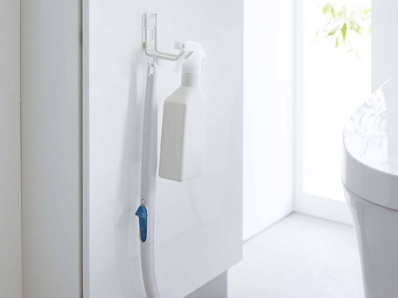 タワーのフィルムフックトイレ用品収納フックがバスルームのタイル面に取り付けられ、プラスチック製のソープディスペンサーやその他の洗面用具が掛けられている様子