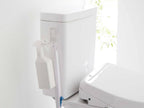 浴室の壁に設置されたタワー型フィルムフックトイレ用品収納フックに、トイレや洗面台の備品が掛けられている様子