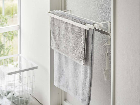 銀色のスチール製タオル掛け棚が浴室扉に取り付けられ、バスタオルが掛かっている様子