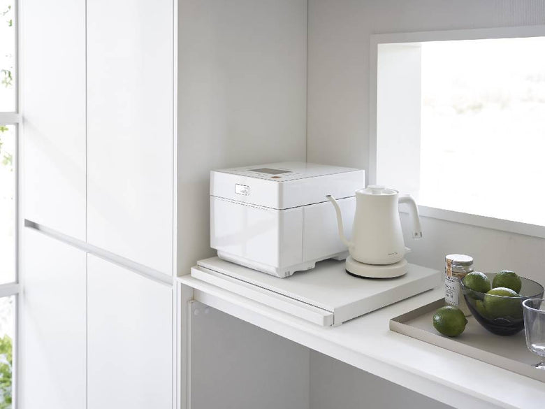 キッチンキャビネット下に設置されたシルバーのタワー型キッチン家電用スライドテーブル。スチールとプラスチック製の棚が収納スペースを提供しています。
