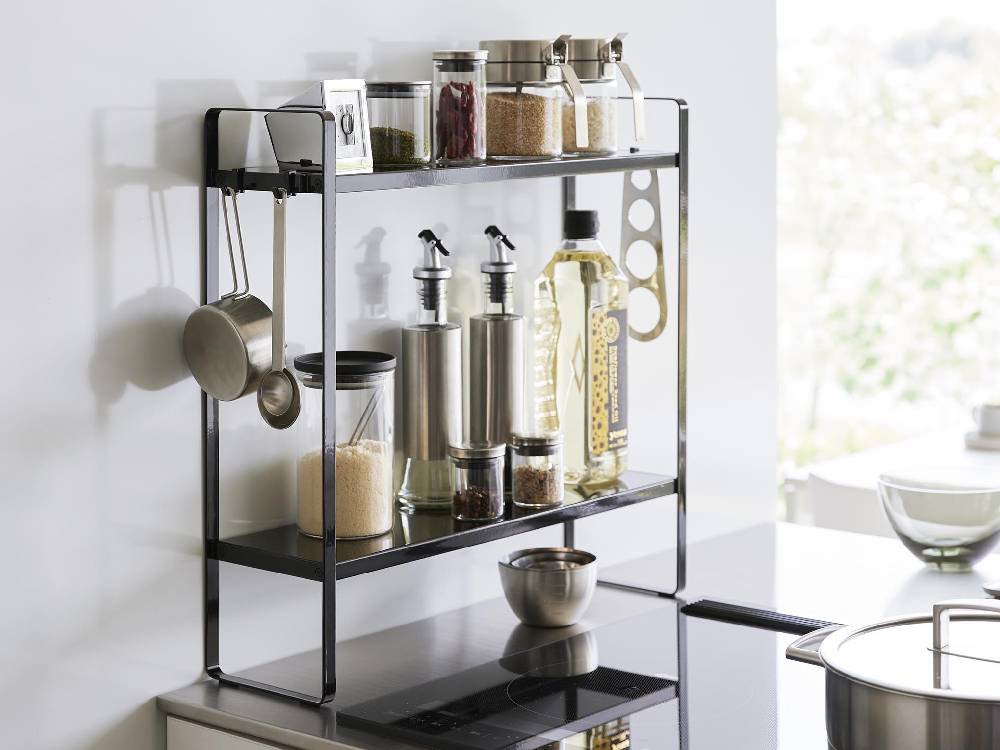 キッチンに設置されたスチール製2段コンロ横ラックに調理器具や瓶が整理されている様子
