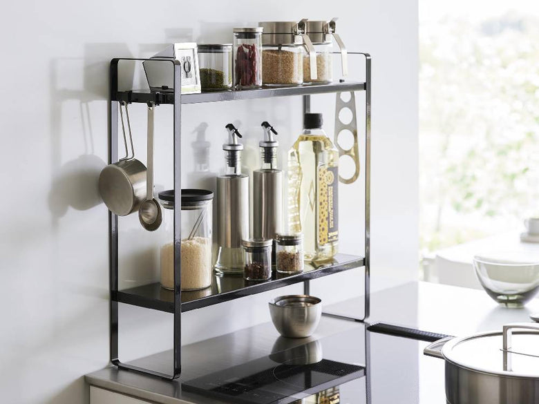 キッチンに設置されたスチール製2段コンロ横ラックに調理器具や瓶が整理されている様子