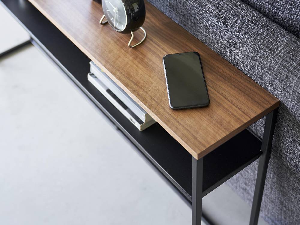 リビングルームに配置された『tower/タワー』ソファー裏コンソールテーブル。スチールと天然木の棚が特徴で、電子機器やガジェットを収納できるモダンなデザイン。