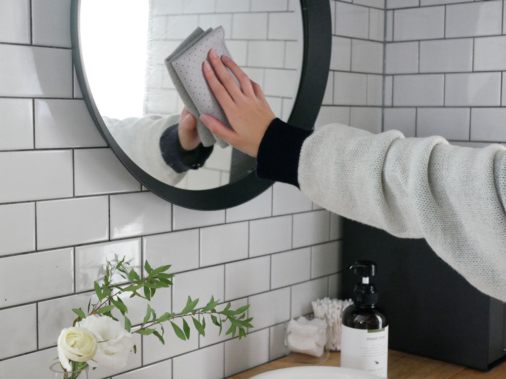 清潔なバスルーム内にウォームグレーの【tidy/ティディ】ワイプクロスが鏡やタイル、配管設備と共に配置されている様子