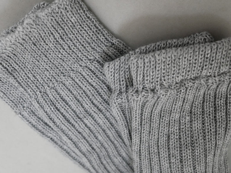 メメリのカシミヤコットン製アーム＆レッグウォーマー。白と灰色の柔らかいウール素材で編まれたニットアクセサリー。