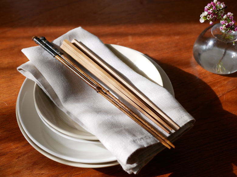 黒竹取り箸とフォーク、プレート、ナプキンなどが整然と並べられた上品な食卓セッティング