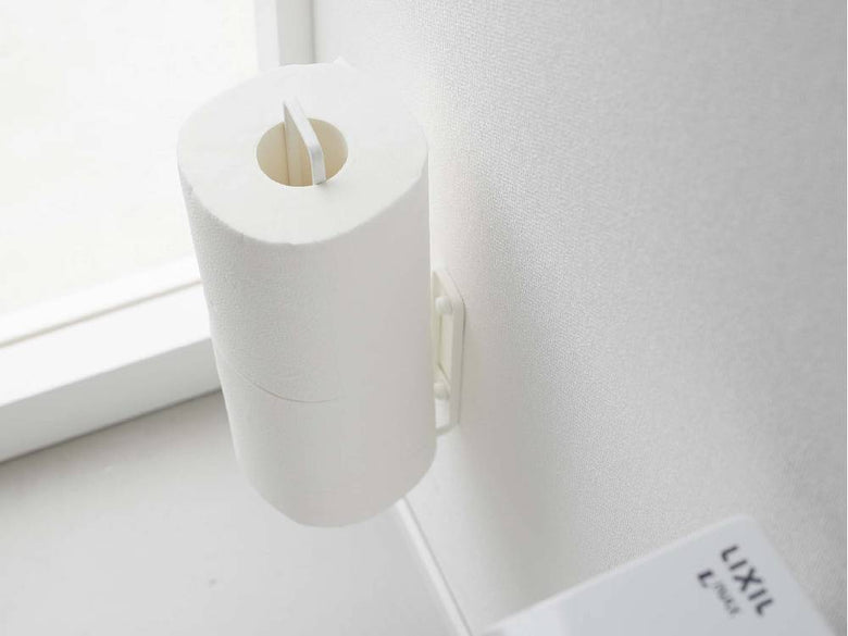 スチール製のタワー型ウォールトイレットペーパーホルダーが壁に取り付けられ、一般的なトイレットロール2本を保持している様子