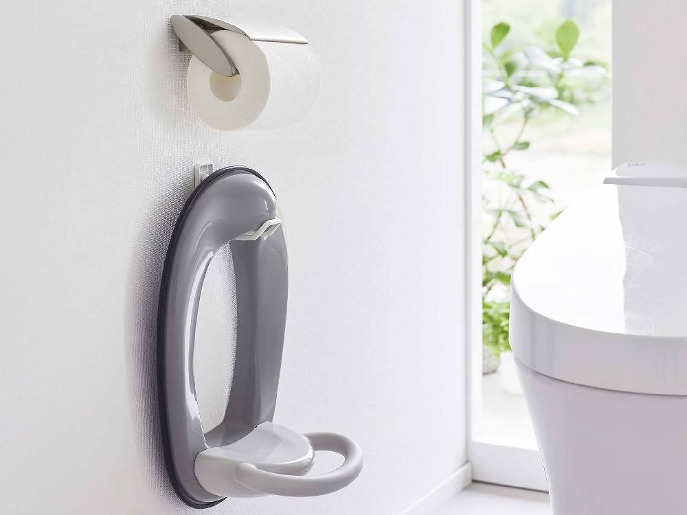 白いトイレの壁に取り付けられたタワーウォールトイレ用品収納フック。銀色のトイレットペーパーホルダー付き