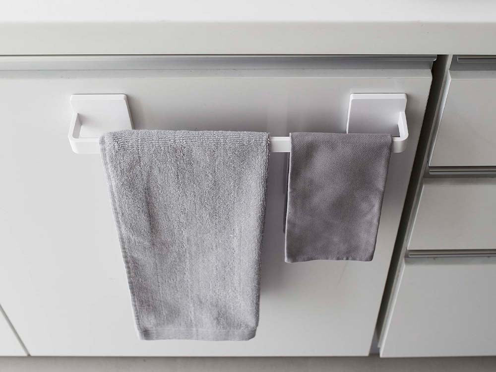 PLATE/プレートのW36ホワイトタオルハンガーが光沢のある壁面に設置され、タオルや台所用布巾が掛けられている様子