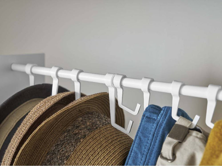 スチール製タワー型帽子収納スタンドに衣類ハンガーが掛けられている様子