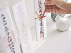 スチール製のスマート神札スタンドに手書きの神札が飾られている写真