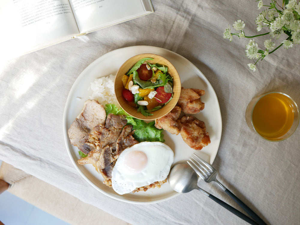 天然木の食洗機対応マルチボールとプレートに盛られた朝食の食卓セット。野菜や肉が並び、木製の食器が整然と配置されています。