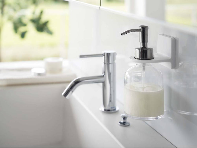 ミストフィルムフックディスペンサーホルダーが浴室の洗面台に取り付けられ、ソープディスペンサーとボトルを整理している様子