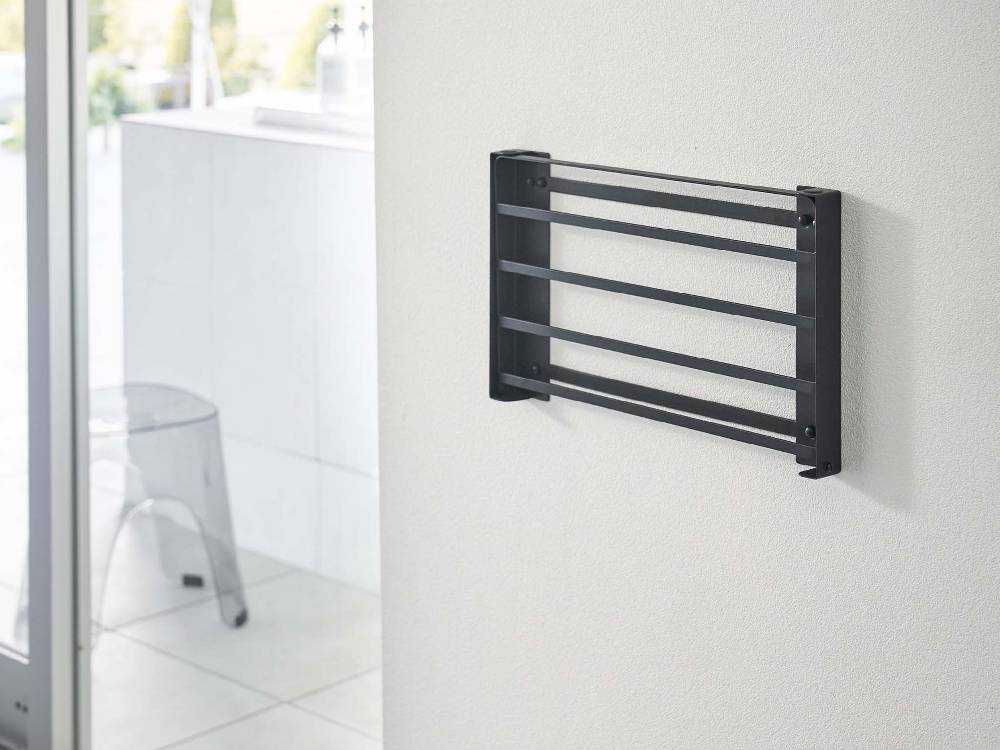 グレー色の折りたたみ棚「tower/タワー」が石こうボード対応の壁に取り付けられている様子