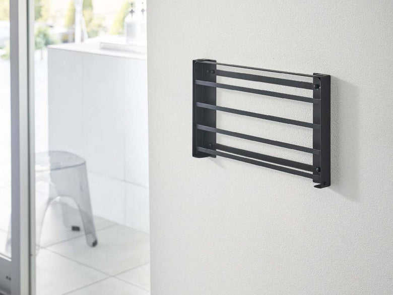 グレー色の折りたたみ棚「tower/タワー」が石こうボード対応の壁に取り付けられている様子