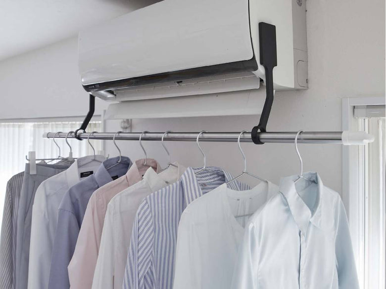 天井にシルバー製のタワー型フィルムフックエアコン室内物干しポールホルダーが取り付けられ、洗濯物が掛けられている様子