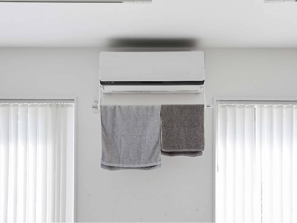 銀色のフィルムフック付きエアコン室内物干しポールホルダーがエアコン本体に取り付けられている様子