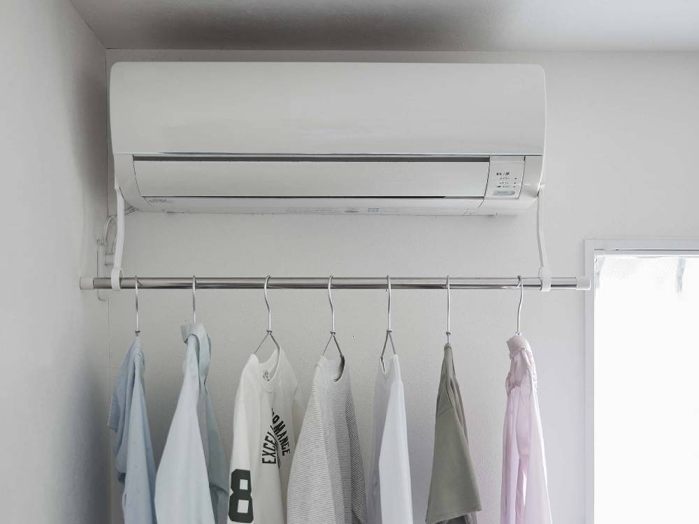 エアコンにフィルムフックで取り付けられた【tower/タワー】室内物干しポールホルダー