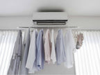 銀色のフィルムフックエアコン室内物干しポールホルダーに衣類が掛けられている様子