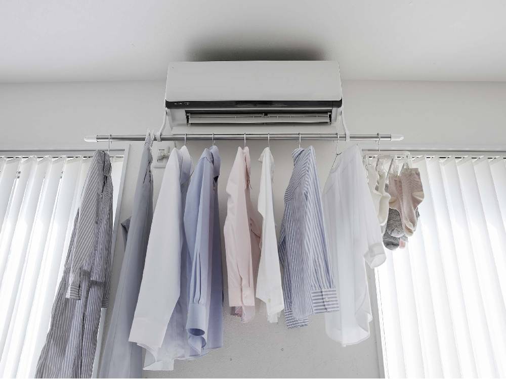 銀色のフィルムフックエアコン室内物干しポールホルダーに衣類が掛けられている様子