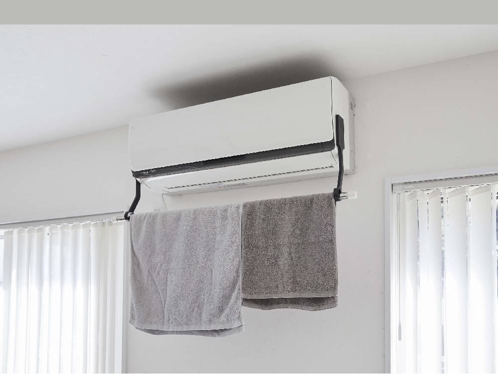 タワー型フィルムフックでエアコンに取り付けられた室内物干し用ポールホルダーの画像