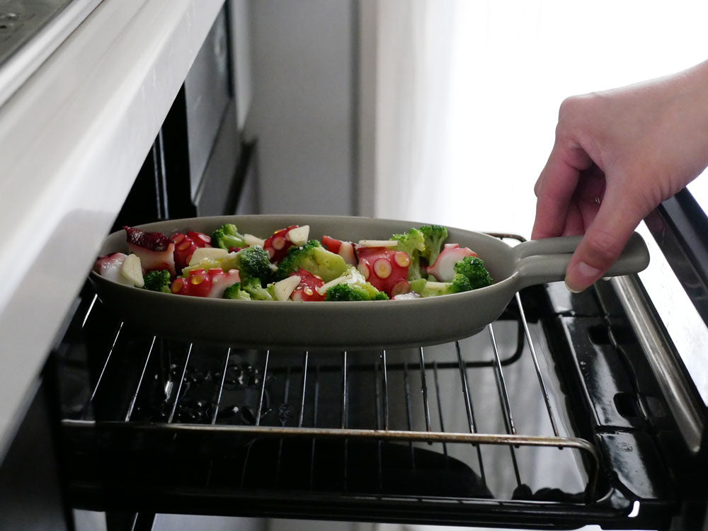 IBUKICRAFTの耐熱陶器製魚焼きグリルプレートと木製ウッドボードが調理中のキッチンでセットされている様子