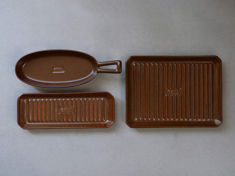 IBUKICRAFTの耐熱陶器製魚焼きグリルプレートとサーヴィングトレイ、食器類が並んだキッチン用品セットの写真