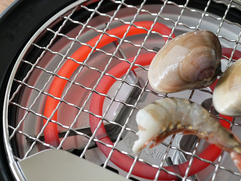 sirocaの多彩なプレートを備えたおうちいろりで、焼き網や深皿を使用して屋外で海鮮をバーベキューしている様子