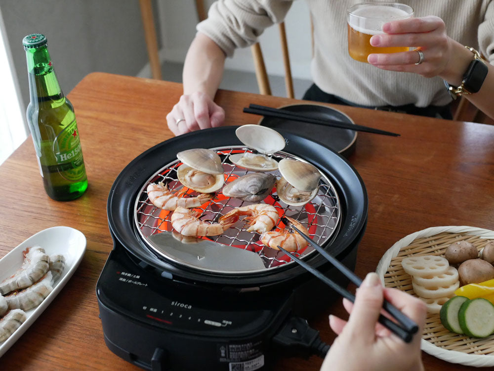 sirocaの多機能おうちいろり本体と付属の調理器具を使用して、家庭のキッチンで肉や野菜を調理している様子