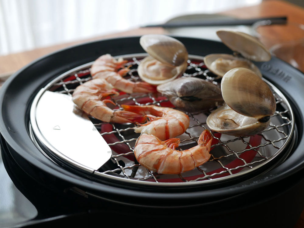 シロカのおうちいろり本体と焼き網にエビや肉が並べられた調理風景