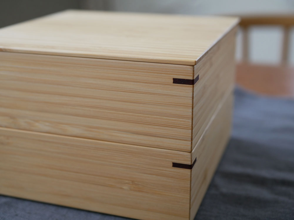 ウレタン塗装された竹製の二段重箱が並んでいる木製の背景画像。