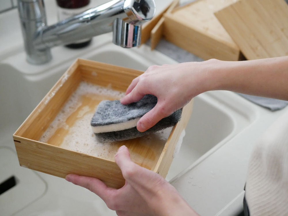 キッチンシンクと水栓、スポンジ、清掃用品、調理器具が並んでいる様子