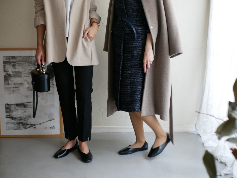 黒色のPU合成皮革スリッポンとポリエステル製携帯ポーチが並んだファッショナブルな靴の画像