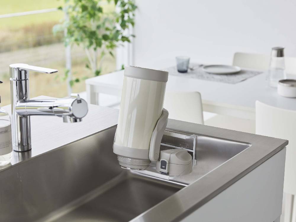 タワー型フィルムフックワイドジャグボトルホルダー Sがキッチンカウンターに設置され、水筒やジャグボトルを掛けている様子