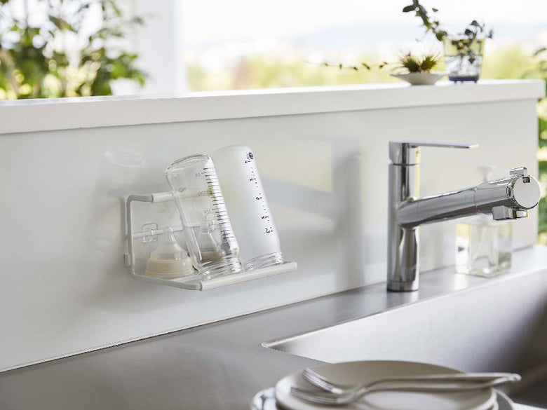 "タワー製フィルムフックワイドジャグボトルホルダーがキッチンの壁に設置され、複数のボトルを掛けている様子"