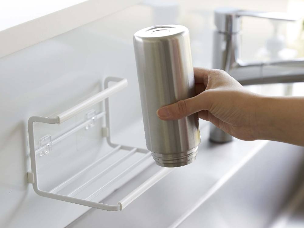 スチール製フィルムフックワイドジャグボトルホルダー Sがキッチンのカウンタートップに設置され、水筒や調理器具を整理整頓している様子