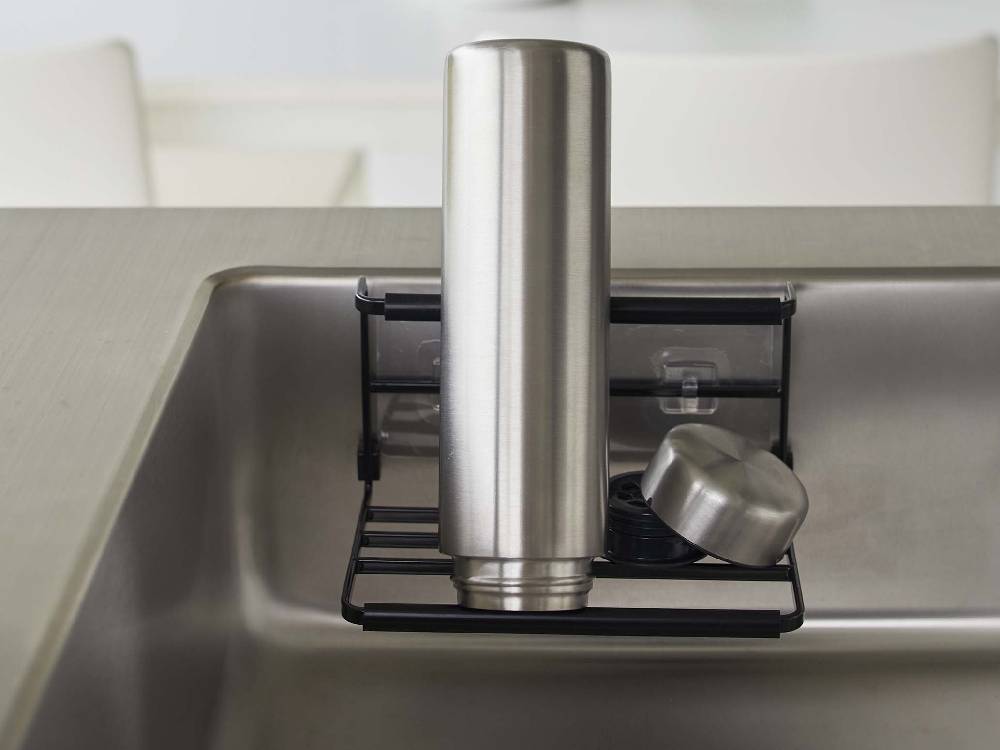 キッチンカウンターに設置されたタワーのフィルムフックワイドジャグボトルホルダー Sが、水筒やジャグボトルを整然と収納している様子