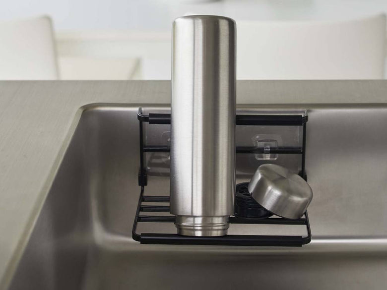 キッチンカウンターに設置されたタワーのフィルムフックワイドジャグボトルホルダー Sが、水筒やジャグボトルを整然と収納している様子