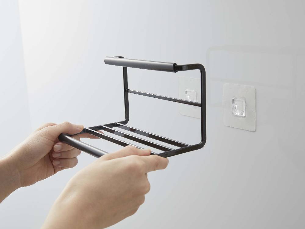 タワー製フィルムフックワイドジャグボトルホルダーSがスチール製の棚に取り付けられ、ガジェットや家庭用品を整理している様子