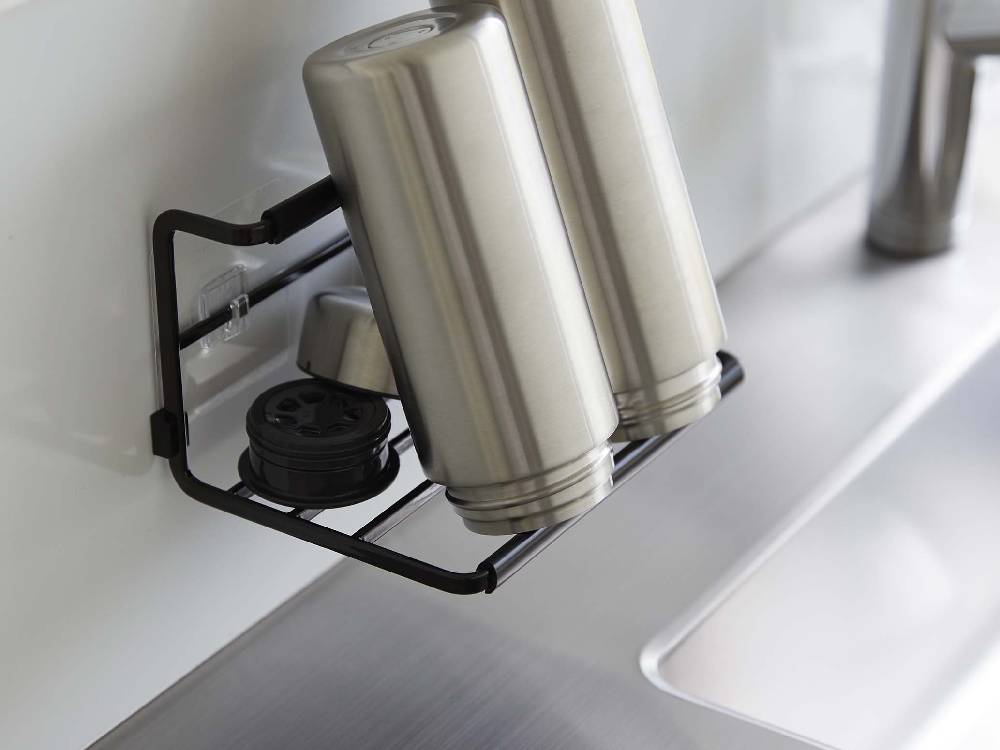 タワーのフィルムフックワイドジャグボトルホルダーSがキッチンのカウンタートップとシンク周辺に設置され、タンブラーやボトルが掛けられている様子。