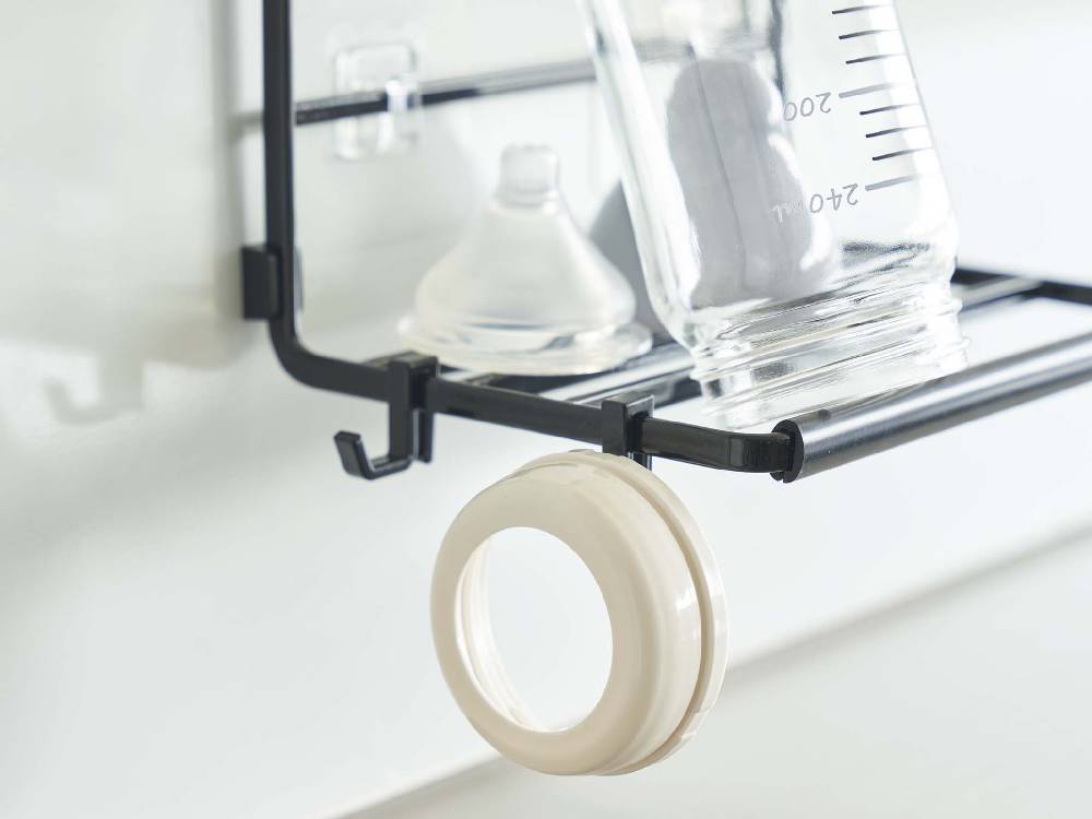 【tower/タワー】フィルムフックワイドジャグボトルホルダー Sがキッチンの棚に設置され、調理器具やパイプと共にディスプレイされている様子