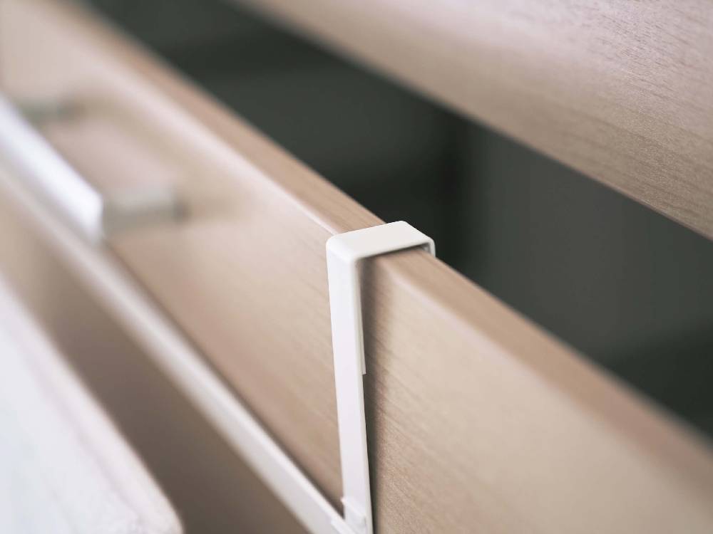 木製の引き出しにスチール製の洗面下引っ掛けバスマットとタオルハンガーが取り付けられている様子